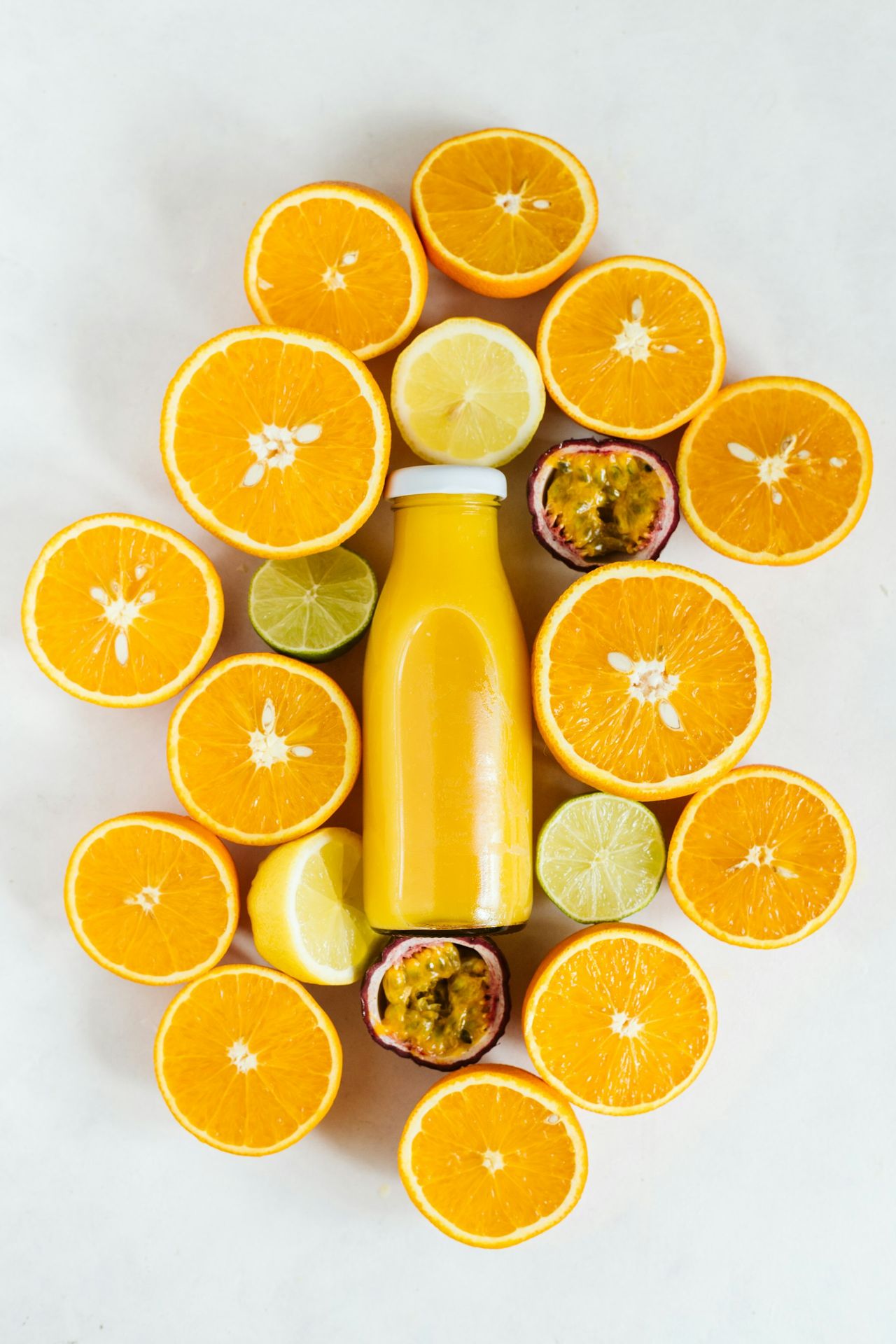Fruta naranja en rodajas junto a una botella llena de líquido amarillo