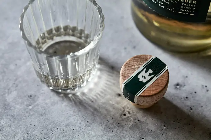 un vaso de agua junto a una botella de alcohol